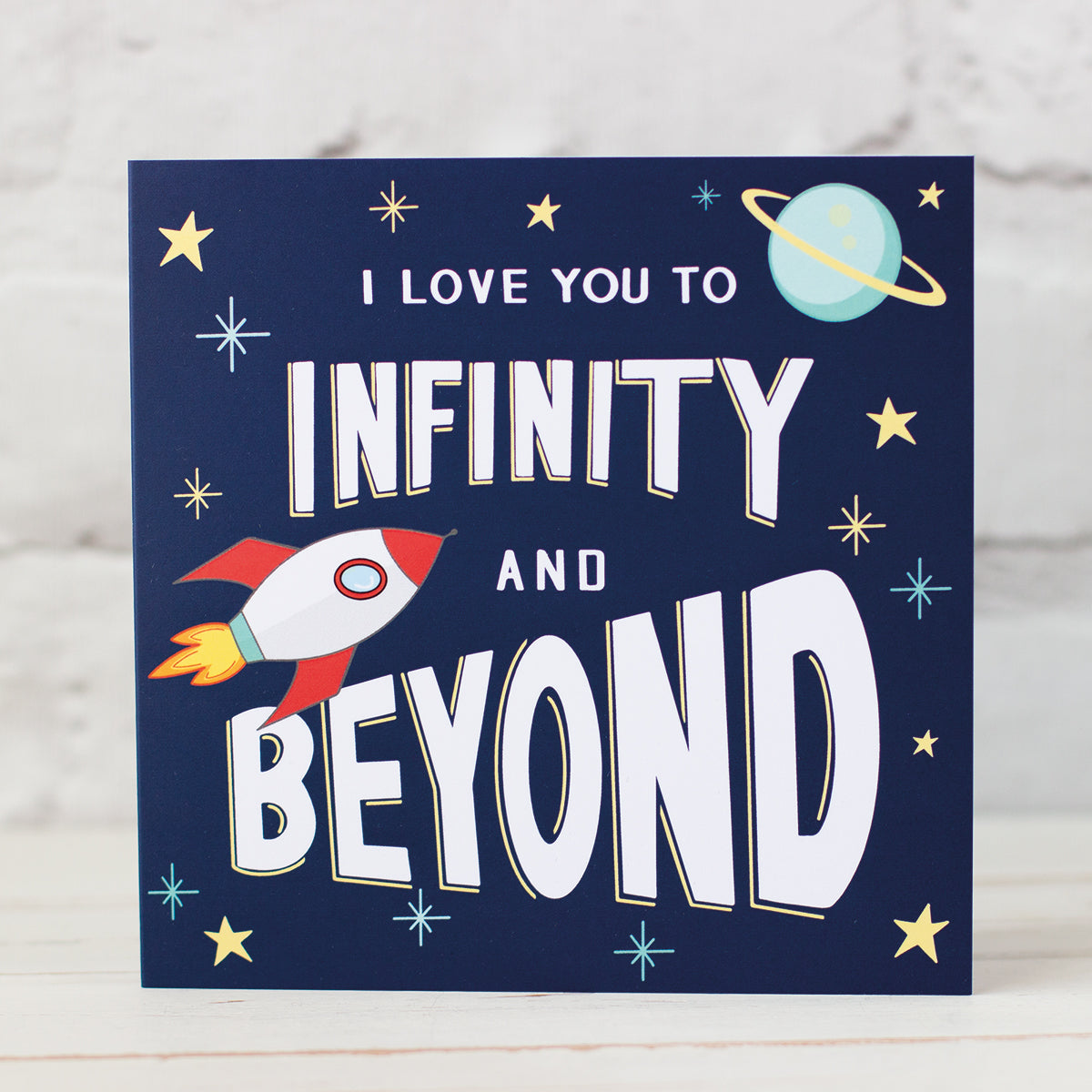 Space themed Valentines, anniversary card. Dark Blue Background white lettering "I Love You to Infinity and Beyond, Design uncludes spaceship, stars and planet