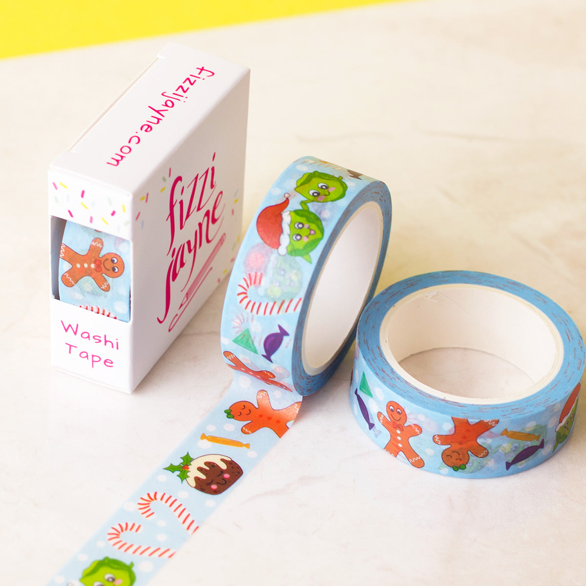 Cute Festive Food Characters Washi tape. Characters include Gingerbread man and woman, sprouts, one with a Santa hat, Christmas pudding on a blue background with white snowballs and candy canes and sweets. Tape is packaged in a box