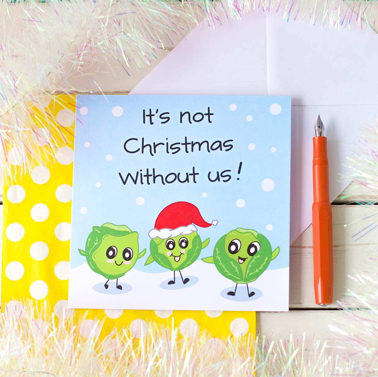 Illustrated Christmas card by fizzi-jayne. Three Cute Kawaii style sprouts, one with a Santa hat on, in the snow with handlettering that says, It's Not Christmas Without us!