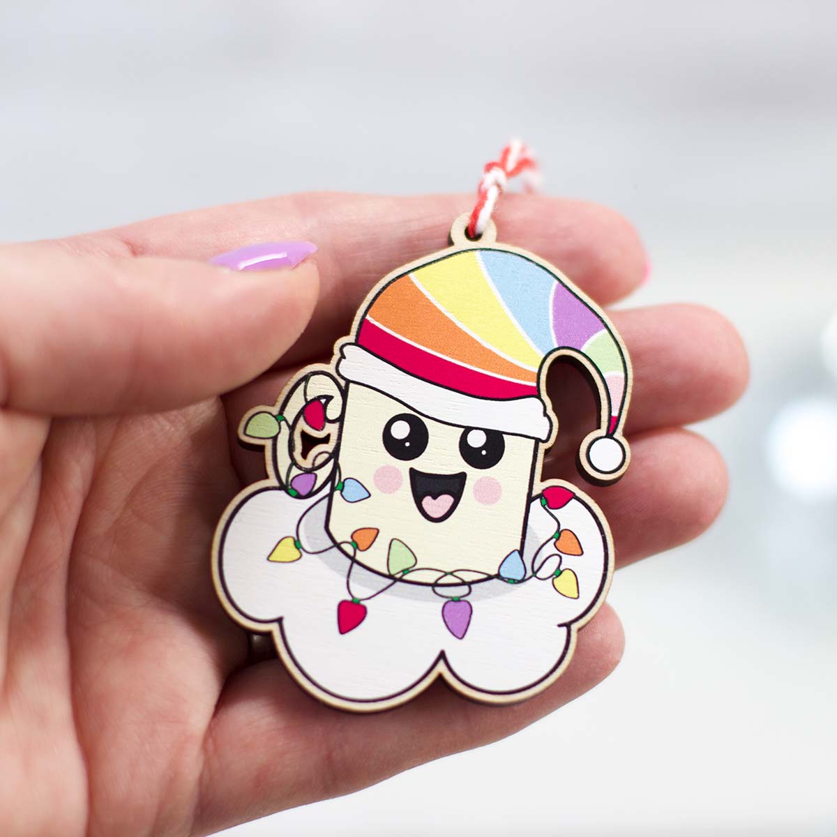 happy, Kawaii style mug on a cloud with a rainbow Santa hat with Christmas lights wrapped around it in the palm of a hand