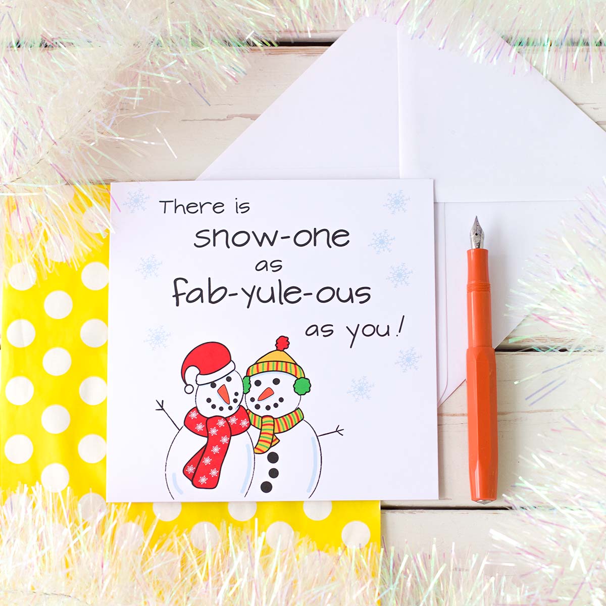 Illustrated Christmas Card by fizzi~jayne. Two snowmen hugging, one wearing a santa hat and red scarf th other with a bobble hat, ear muffs and scarf.  The handkettering reads There is Snow-one as fab-yule-ous as you!