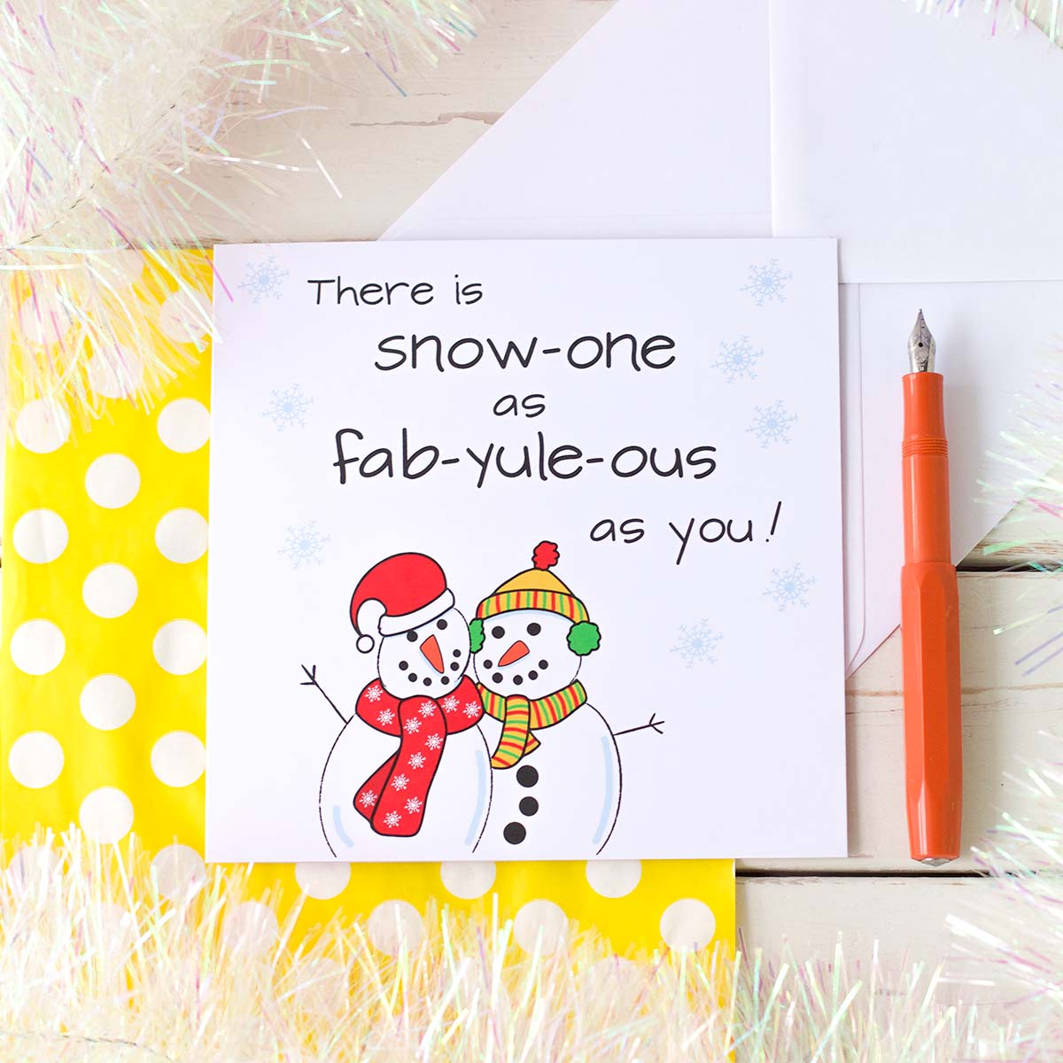 Illustrated Christmas Card by fizzi~jayne. Two snowmen hugging, one wearing a santa hat and red scarf th other with a bobble hat, ear muffs and scarf. The handkettering reads There is Snow-one as fab-yule-ous as you!