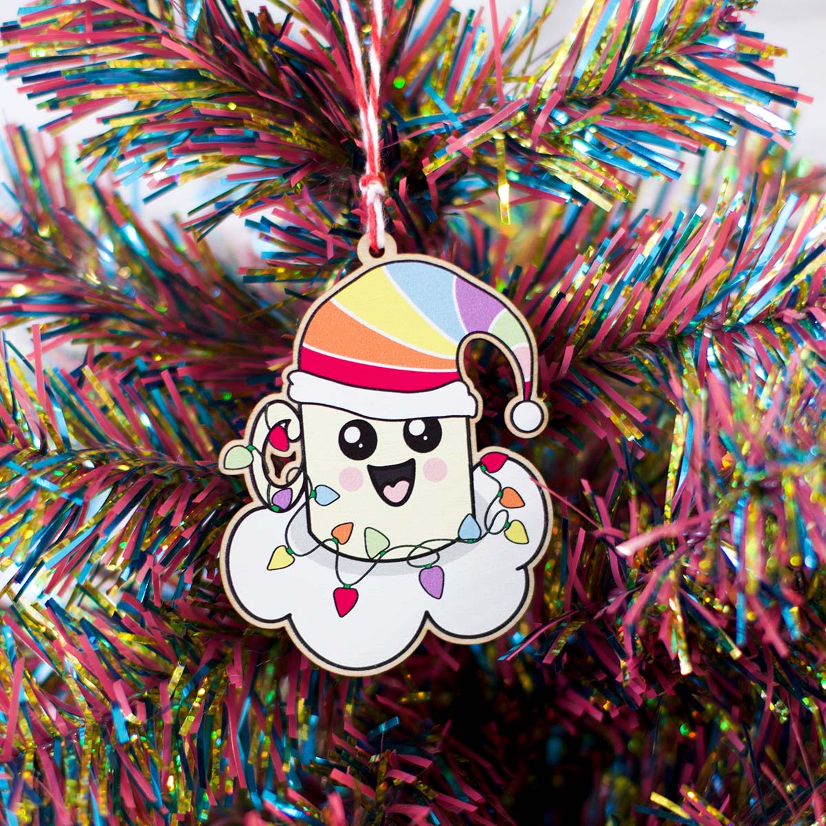 quirky, original Christmas tree hanging decoration. happy, Kawaii style mug on a cloud with a rainbow Santa hat with Christmas lights wrapped around it 